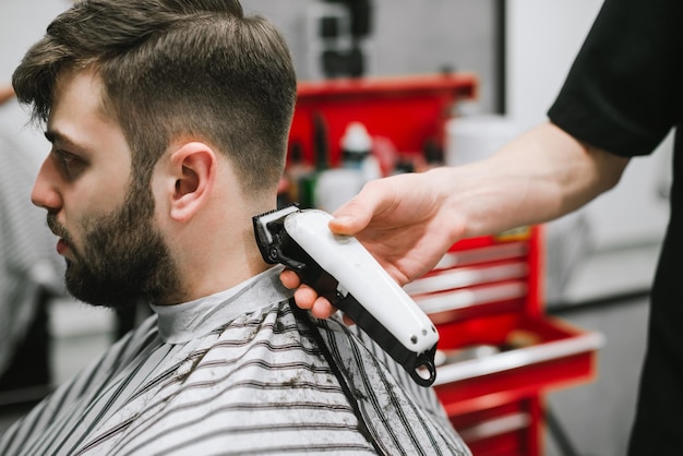 Peluquería corta a un cliente en una barbería de cerca