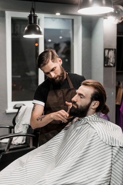 Foto peluquería cortando la barba del cliente en peluquería