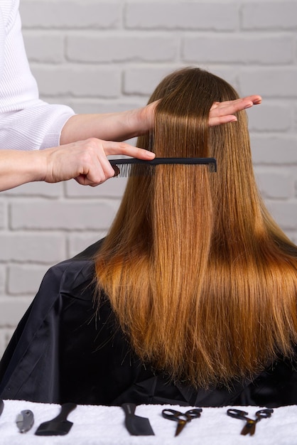 Peluquería de cuidado de cabello de mujer haciendo peinado a niña en salón de belleza