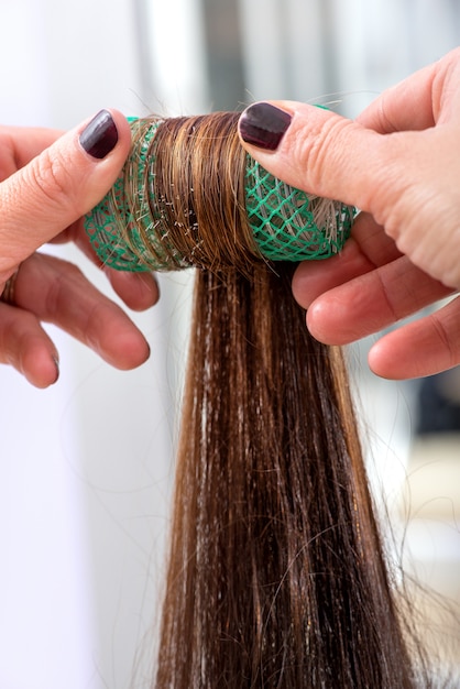 Peluquería enrollando el cabello de un cliente en un rodillo