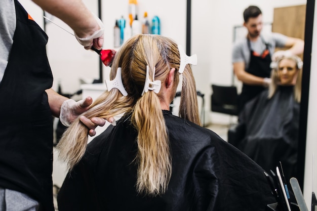 Peluquería está muriendo raíces de cabello de mujer madura.