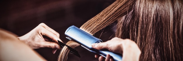 Peluquería femenina alisar el cabello de un cliente