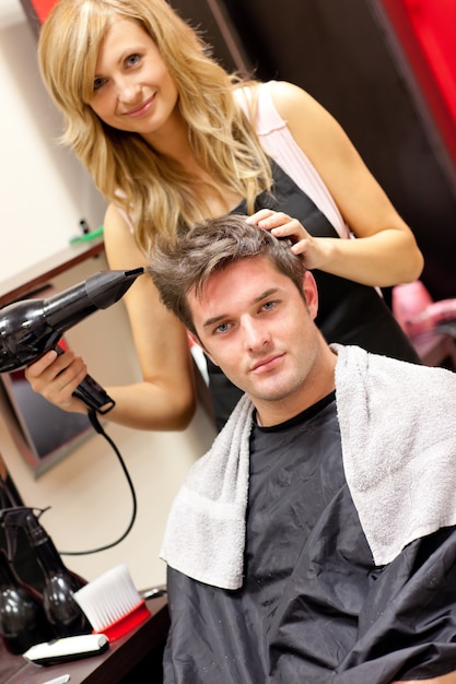 Peluquería femenina profesional secar el cabello de su cliente