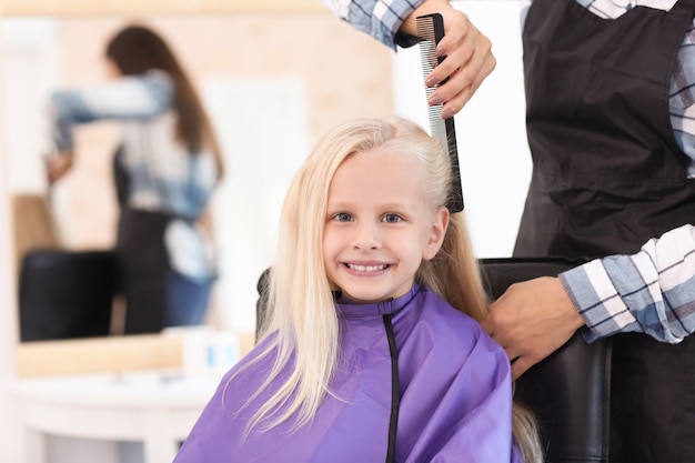 Peluquería femenina que trabaja con la niña en el salón, primer plano