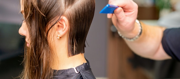 Peluquería haciendo corte de pelo de mujer joven