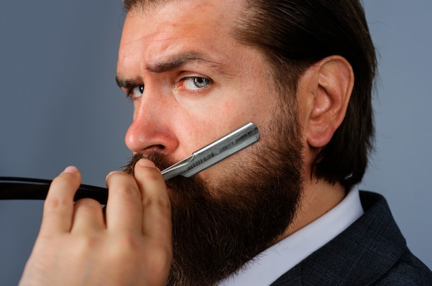 Peluquería. Hombre barbudo con navaja de peluquero. Cuidado profesional de la barba. Peluquero. Salón para hombres.