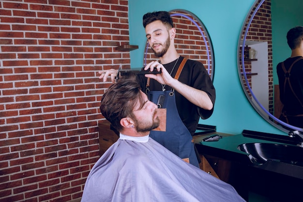 Peluquería joven cortando el cabello de un cliente masculino. foto de alta calidad