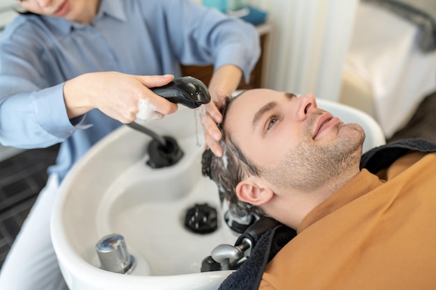Foto peluquería lavando el cabello al cliente masculino en un salón de belleza