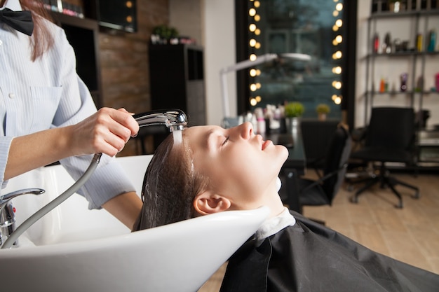 Peluquería lavar el cabello de la mujer antes del corte de pelo. Tiro horizontal en interiores