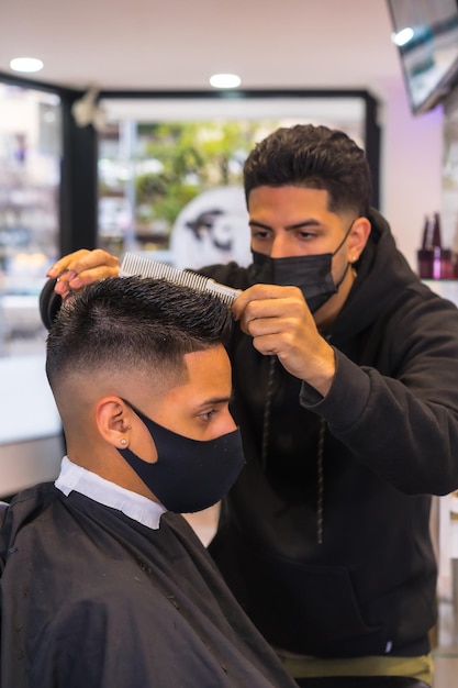 Peluquería con mascarilla cortando el pelo