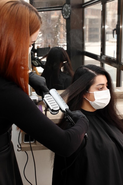 Peluquería con mascarilla médica trabaja en el salón.