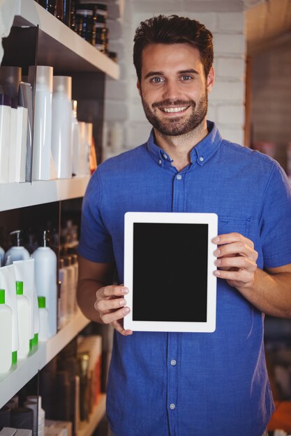 Peluquería masculina sonriente que muestra la tableta digital