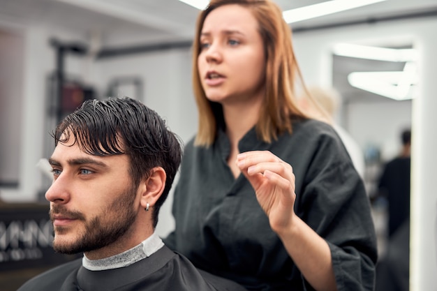 Foto peluquería mujer corte cabello guapo hombre caucásico en peluquería moderna