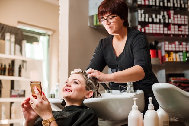 Peluquería y mujer durante el lavado del cabello.