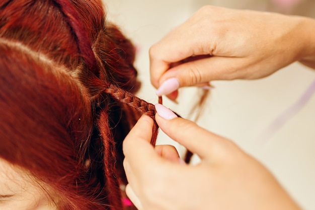 Peluquería de niña teje rastas de jengibre de mujer cerca del proceso de trenzado trenzas africanas con col ...