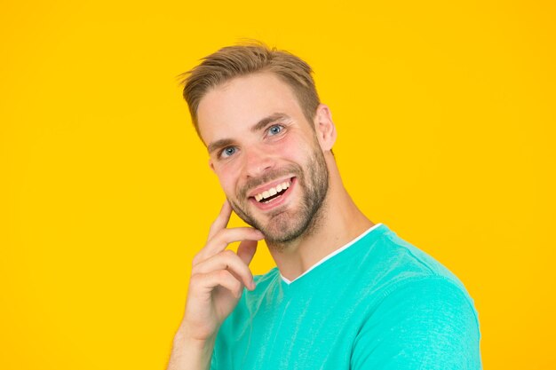 Peluquería Peluquería Hombre barbudo Cuidado de la piel Cuidado facial Mantener la juventud Sonrisa amable Cuidado personal Hombre guapo fondo amarillo Chico bien arreglado con cerdas y peinado agradable Belleza masculina