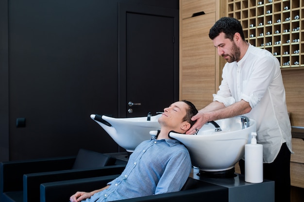 Peluquería Peluquería Lavar el cabello del cliente - Joven relajante en peluquería Salón de belleza