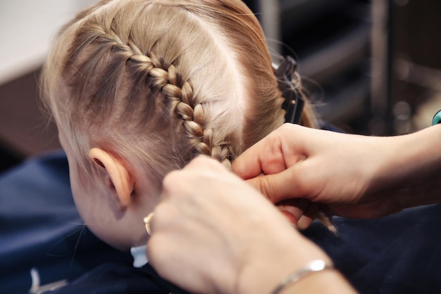 Peluquería peluquero hace trenzas de peinado para bebé en peluquería Peluquería mujer hacer peinado de moda