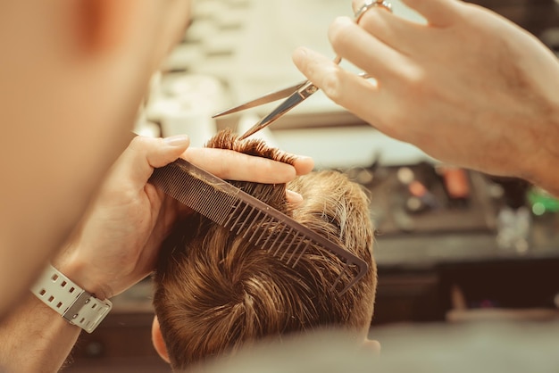 Peluquería. Primer plano del corte de pelo del hombre, el maestro hace el peinado en la peluquería. Fotos antiguas en tonos.