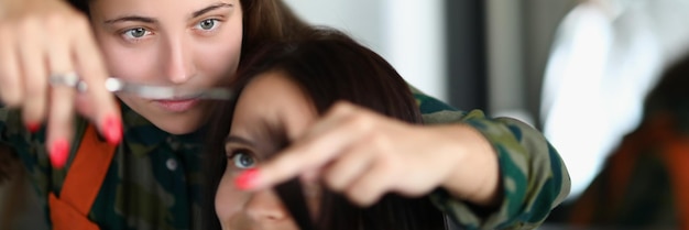 Peluquería profesional concentrada sosteniendo un mechón de cabello y cortando con tijeras