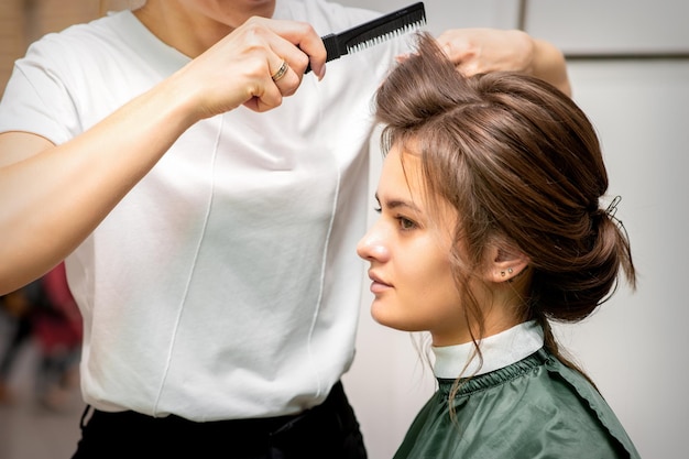 Peluquería profesional haciendo peinado para una hermosa joven morena con cabello largo. Concepto de moda y belleza.