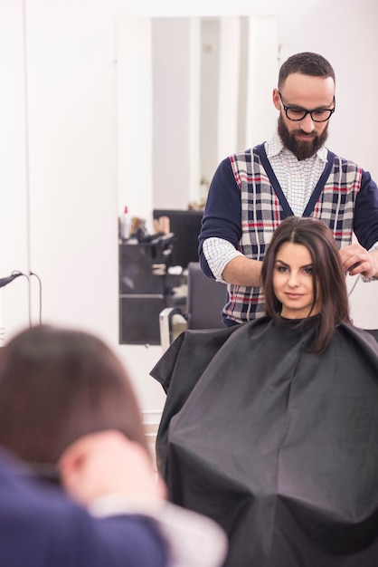 Peluquería profesional haciendo el pelo para una chica morena.