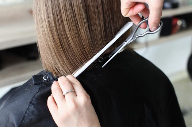 Peluquería recortando cabello castaño con tijeras