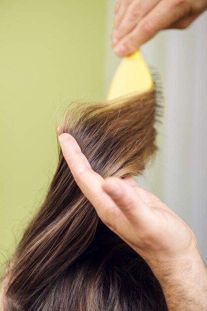 Foto peluquería secando el cabello castaño largo con cepillo.