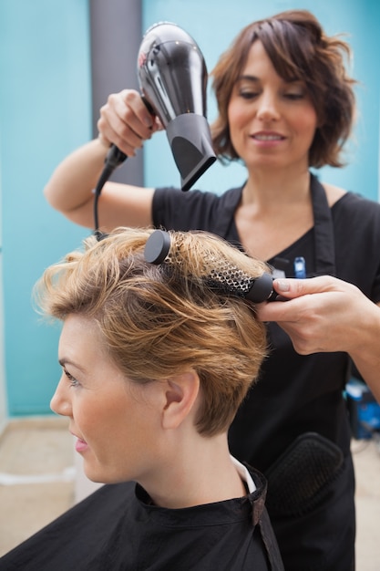 Peluquería secando el cabello de un cliente