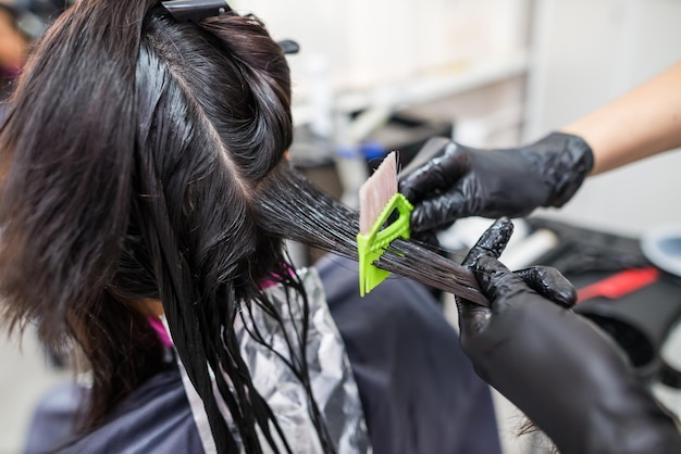 El peluquero aplica queratina líquida profesional al cabello del cliente Una niña fortalece el cabello con queratina en un salón de belleza Cuidado del cabello