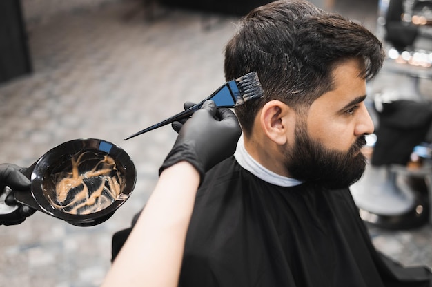 El peluquero aplica tinte al cabello de los clientes con un cepillo