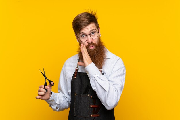 Peluquero con barba larga en un delantal amarillo susurrando algo