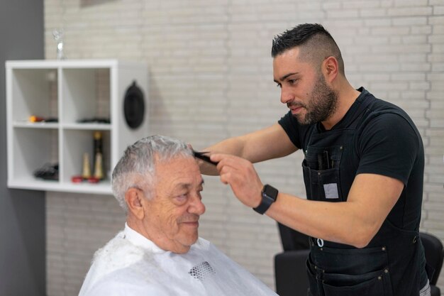 Peluquero concentrado cortando el cabello de un anciano