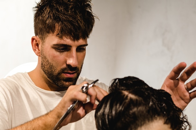 Peluquero concentrado haciendo corte de pelo perfecto