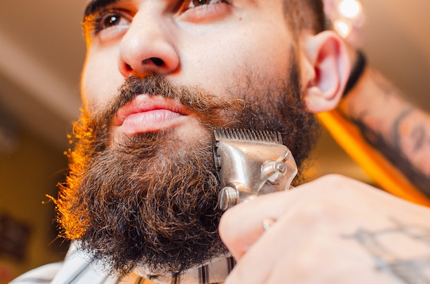 Peluquero corta una barba de cortapelos vintage