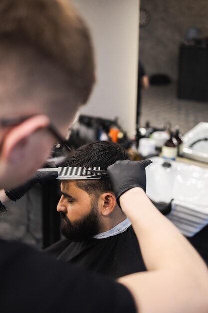 Peluquero corta el cabello en la cabeza de los clientes con tijeras