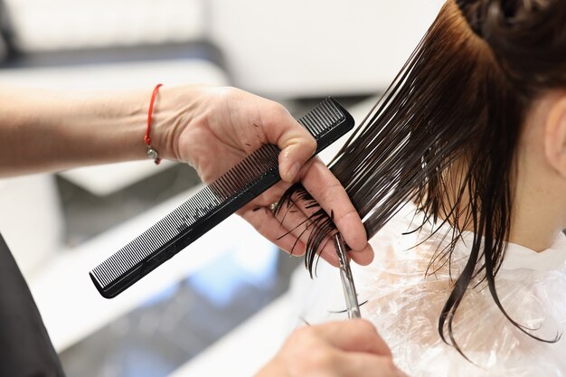 peluquero corta el cabello de los clientes con tijeras