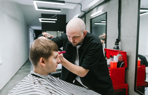 Peluquero corta el pelo en la cabeza de un chico guapo Concepto de peluquería