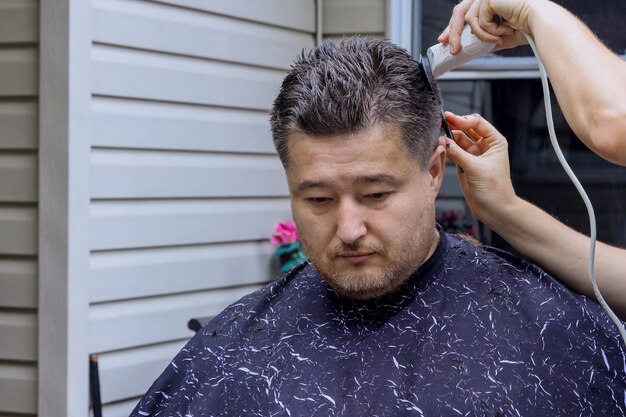 Peluquero cortando el cabello de un hombre en una casa