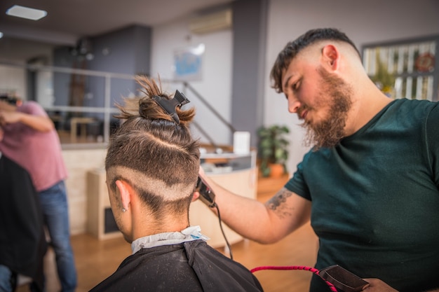 Peluquero cortando el cabello de su cliente en una barbería