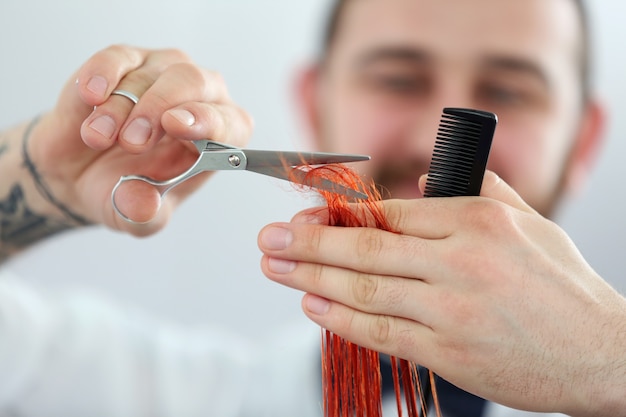 Peluquero cortando rizos rojos