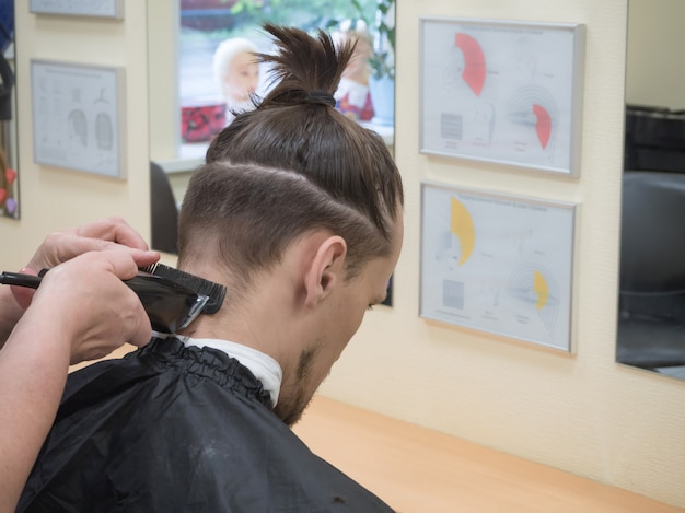 Foto peluquero con cortapelos funciona en el corte de pelo de barbudo barbudo.