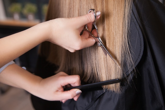 Peluquero cortó el pelo rubio de una mujer. De cerca.