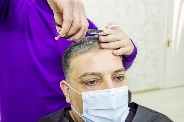 El peluquero está cortando el cabello de los clientes en la barbería.