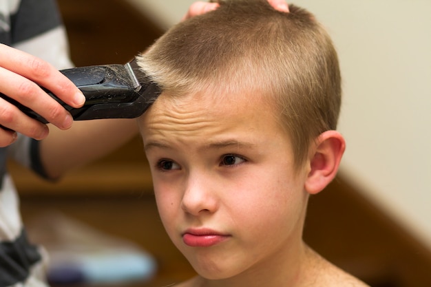 Peluquero está cortando el cabello de un niño en una peluquería