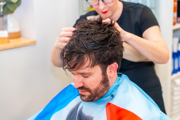 Un peluquero fija una nueva prótesis capilar en la cabeza de un hombre