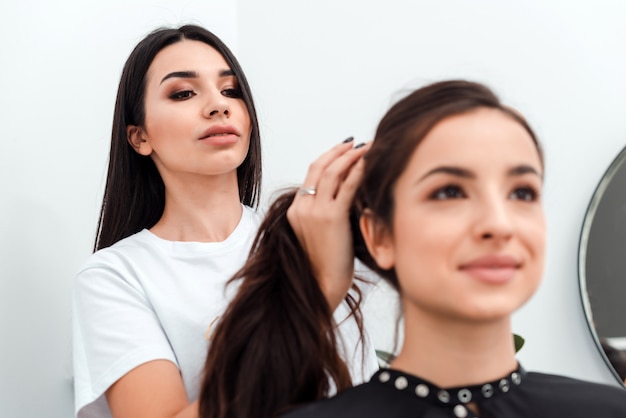 Peluquero hace peinado para mujer joven en salón de belleza