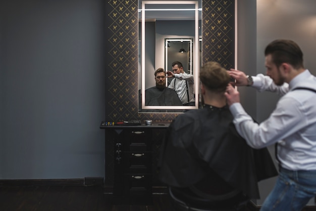 Peluquero haciendo corte de pelo para el cliente