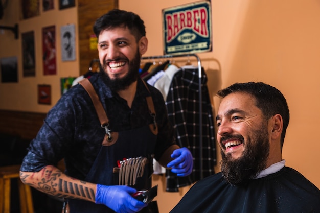 Foto peluquero latino recortando la barba del cliente