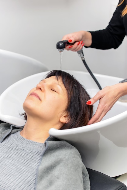 El peluquero lava el cabello y le quita la pintura a la mujer en el salón.